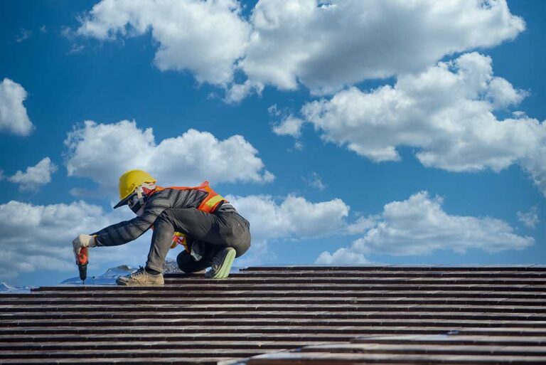 A person safely clearing leaves and debris from a residential home roof on a mild, overcast day.