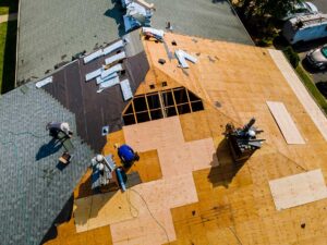 Homeowner examining curled shingles and weathered flashing from the ground beside a house
